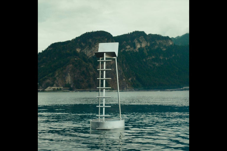 Navigační bóje na jezeře s horami v pozadí.