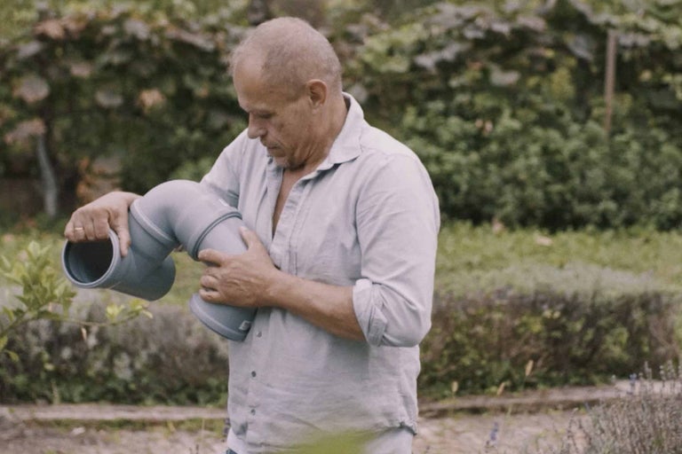 Muž drží v ruce odpadní trubku vhodnou pro sanitární instalace.