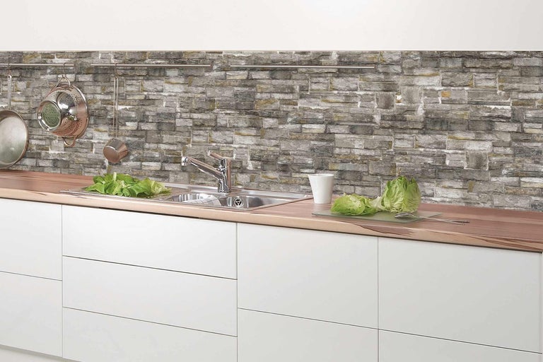 Kuchyňská scéna s dřezem, vodovodní baterií a dekorem kamenné zdi