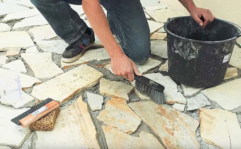 Osoba spáruje podlahové desky s nářadím, kartáčem a kbelíkem.