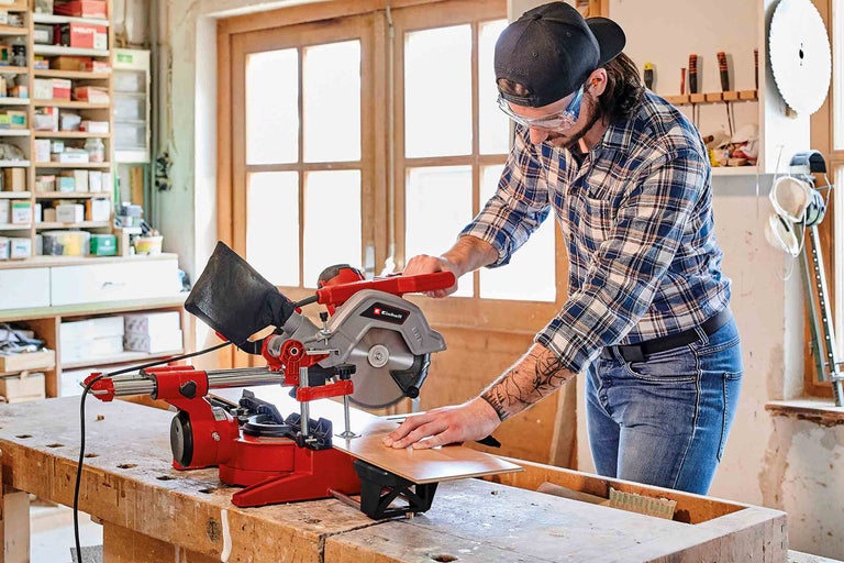 Muž pracuje s pokosovou pilou Einhell na kusu dřeva.
