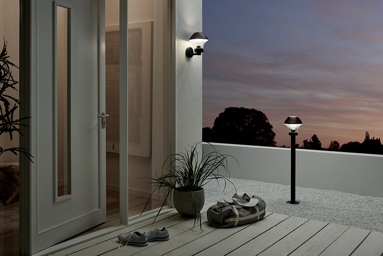 Terasa s venkovním osvětlením, dveřmi, sportovní taškou a botami za soumraku