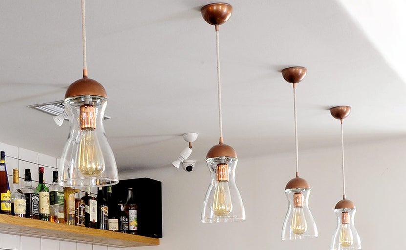 Několik závěsných svítidel s čirým skleněným stínidlem a světelným zdrojem pod stropem