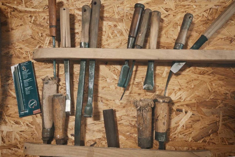 Nářadí, jako jsou dláta a pilníky, na dřevěné polici před dřevotřískovou deskou