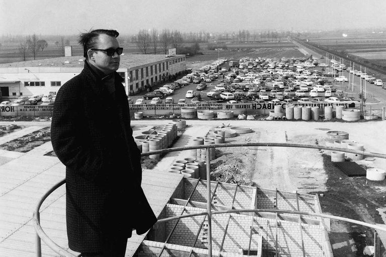 Černobílý snímek prvního hobbymarketu Hornbach s parkovištěm, stavebními materiály a mužem