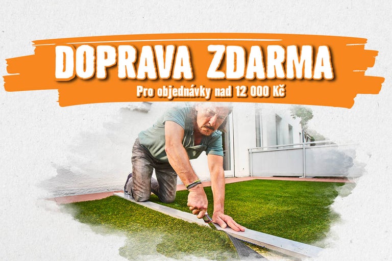 Muž klečí na terase a ořezává umělý trávník pomocí nože podél vodicí lišty.