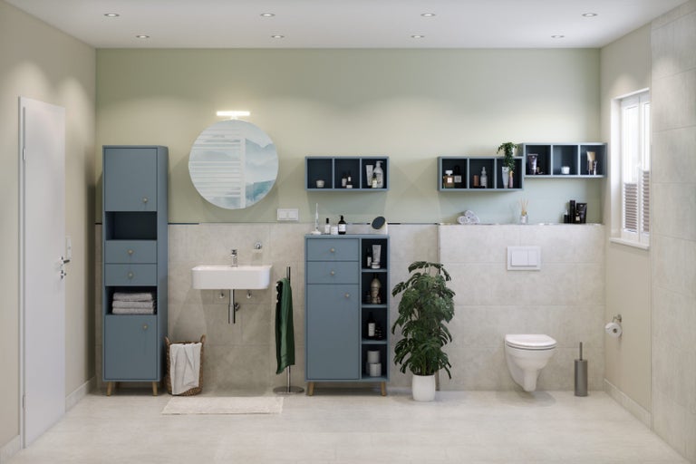 Světlá koupelna s modrým koupelnovým nábytkem, umyvadlem, toaletou a dekoracemi