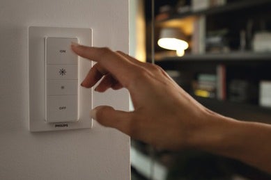 Ruka ovládá stmívač Philips Hue na zdi.