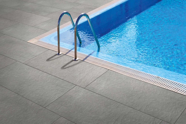 Bazén s šedými terasovými dlaždicemi a žebříkem