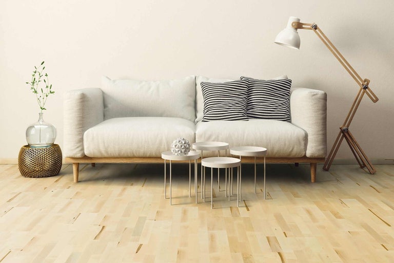 Obývací pokoj s pohovkou, polštáři, odkládacími stolky, stojací lampou a dekorací na dřevěné podlaze.