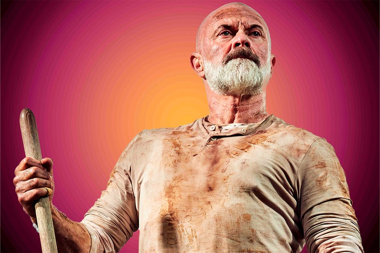 Portrét muže s vousy a špínou na oblečení, který drží dřevěnou hůl