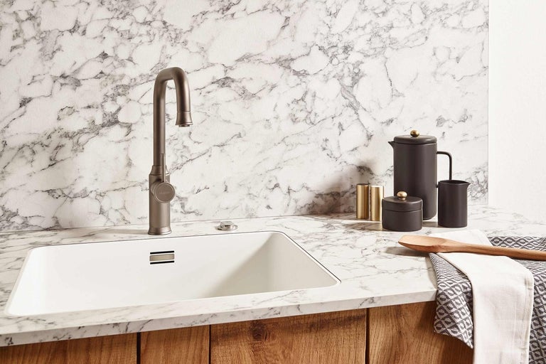 Kuchyňská scéna s dřezem, baterií a kuchyňským náčiním na mramorové desce