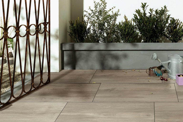 Terasa s dřevěnou podlahou, rostlinami a zahradním příslušenstvím