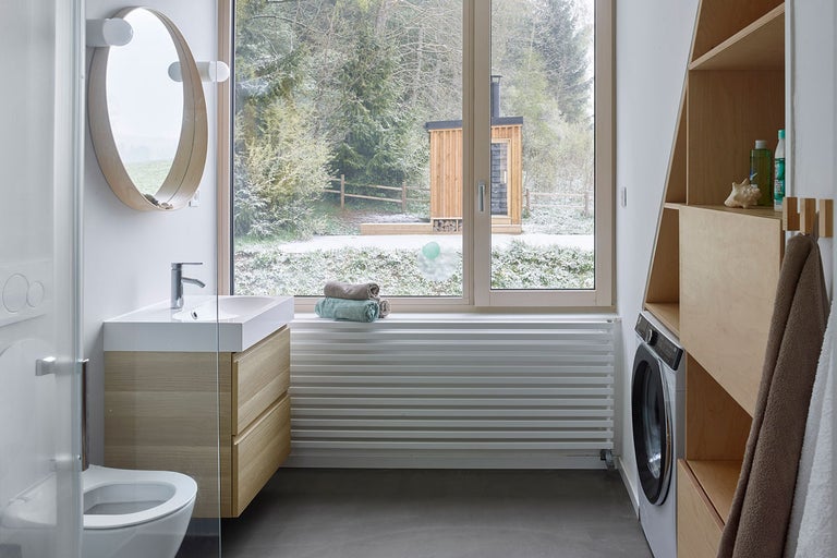 Moderní koupelna s umyvadlem, zrcadlem, radiátorem, pračkou a výhledem ven