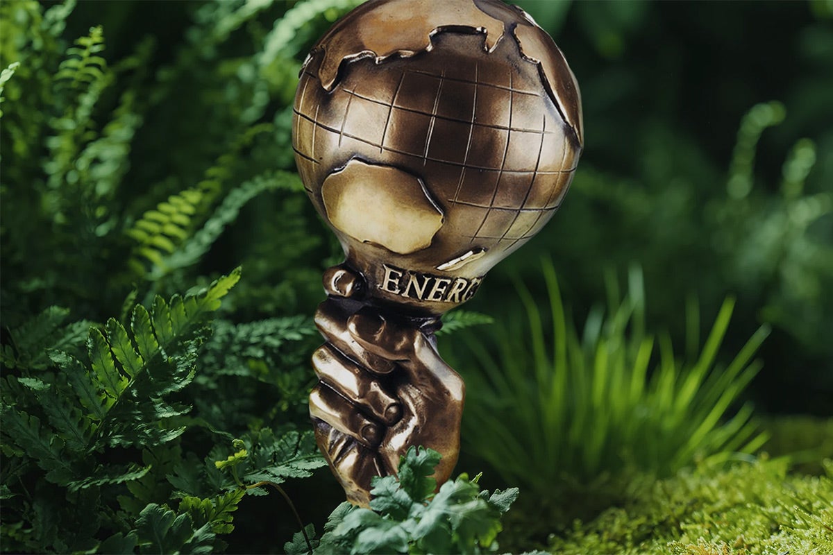 Globus trofej s nápisem Energie v zeleni rostlin