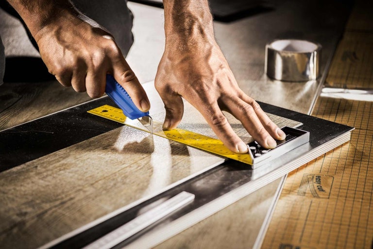 Řezání laminátové desky s odlamovacím nožem a úhelníkem