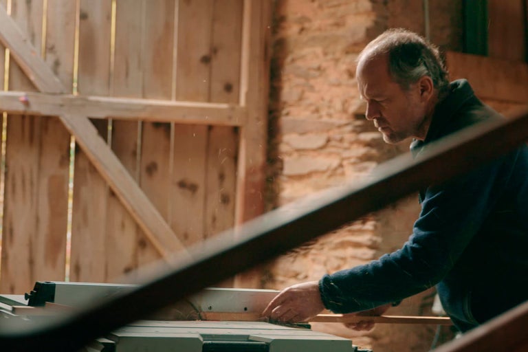 Muž pracuje s kotoučovou pilou v dílně na řezání dřeva.