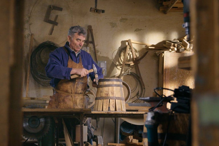 Řemeslník vyrábí v dílně dřevěný sud s kladivem.