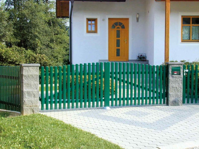 Zelený kovový plot s bránou před domem.