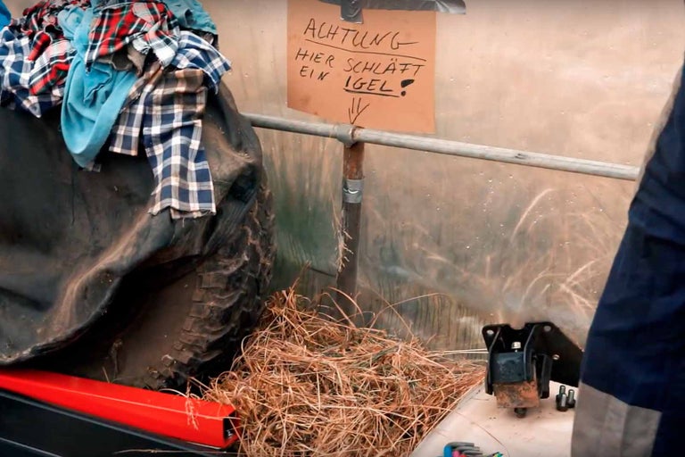 Scéna s pneumatikou, slámou a cedulkou s nápisem Pozor, spí tu ježek