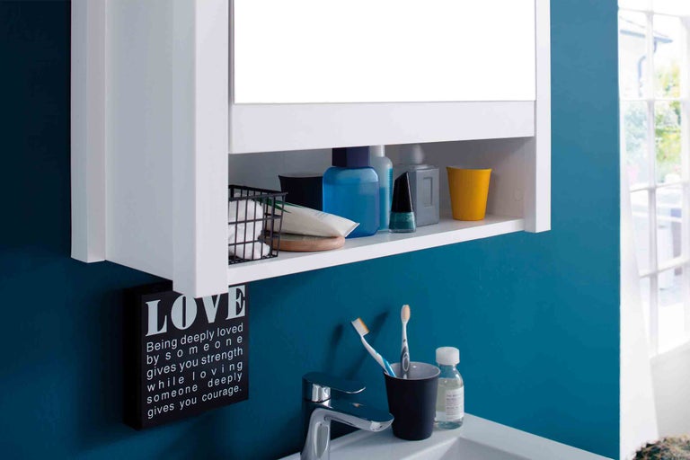 Koupelna s bílou zrcadlovou skříňkou a různými koupelnovými doplňky