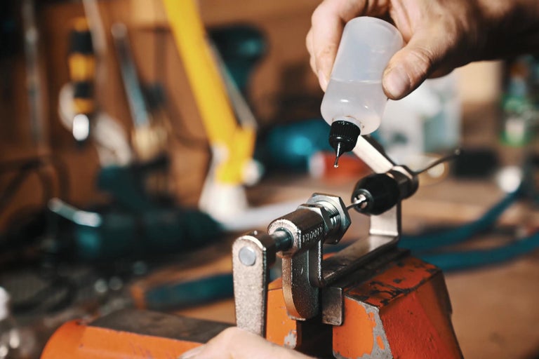 Osoba olejující obrobek upevněný ve svěráku