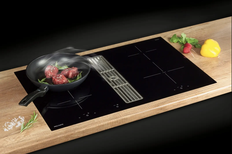 Černá varná deska s odsavačem par a pánví na pracovní desce