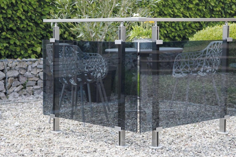 Zahradní scéna se skleněným plotem a nerezovými sloupky na štěrkovém povrchu