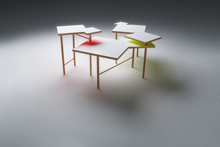 Několik spojených odkládacích stolků ze dřeva a lakované desky.