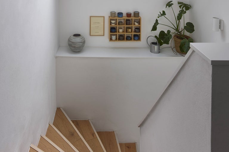 Světlá místnost se schodištěm, dekoracemi a pokojovou rostlinou