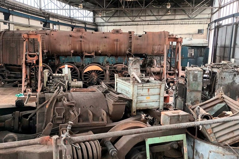 Zrezivělá parní lokomotiva v tovární hale.