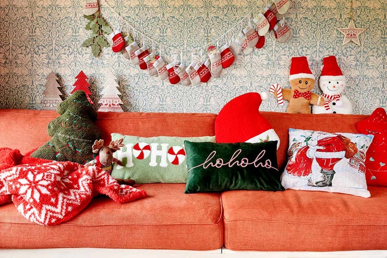 Ozdobný obývací pokoj s vánočními motivy na oranžové pohovce.
