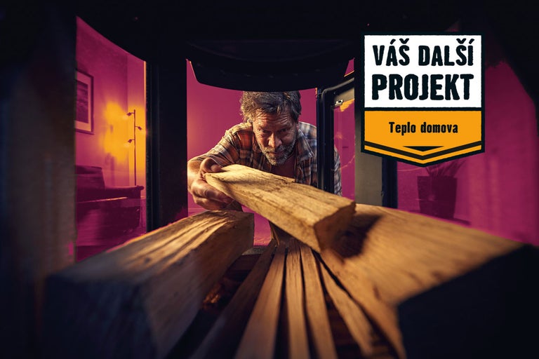 Muž vkládá polena do krbu pro projekt výroby tepla.