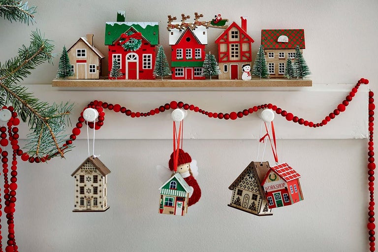 Ozdobné dřevěné domovní ozdoby s červeným korálkovým girlandou na polici