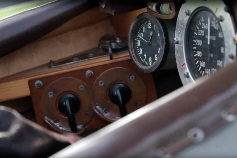 Detailní záběr na kokpit historického letadla s hodinami, rychloměrem a spínači.