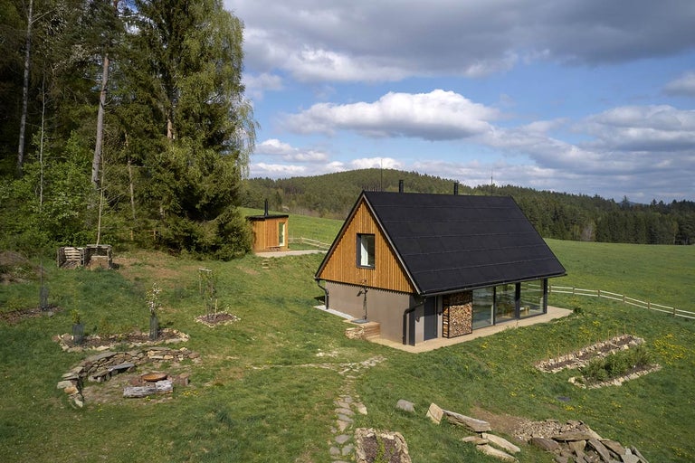 Krajinný pohled na dřevěný dům s černou střechou a vedlejší budovou