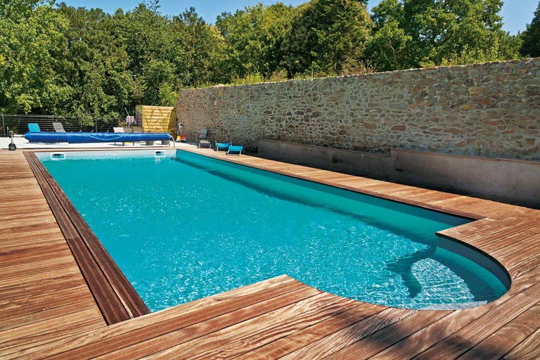 Bazén s dřevěnou terasou a kamennou zdí v zahradě