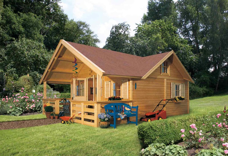 Dřevěný zahradní domek s verandou, zahradním nábytkem a sekačkou na trávu na zahradě.