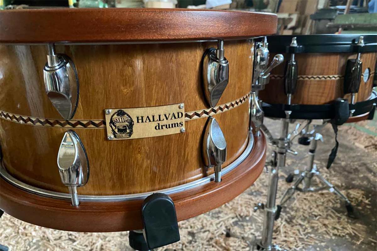 Dřevěné bicí s kovovými držáky a logem Hallvad Drums