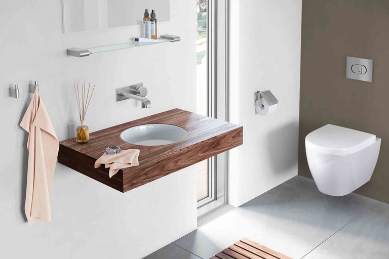 Moderní koupelna s dřevěným umyvadlem, závěsným WC a odpovídajícími doplňky.