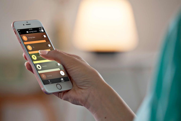 Osoba ovládá osvětlení pomocí aplikace pro chytré telefony