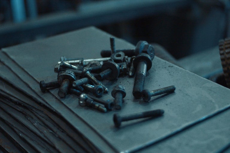 Sbírka různých šroubů a matic na kovovém povrchu.