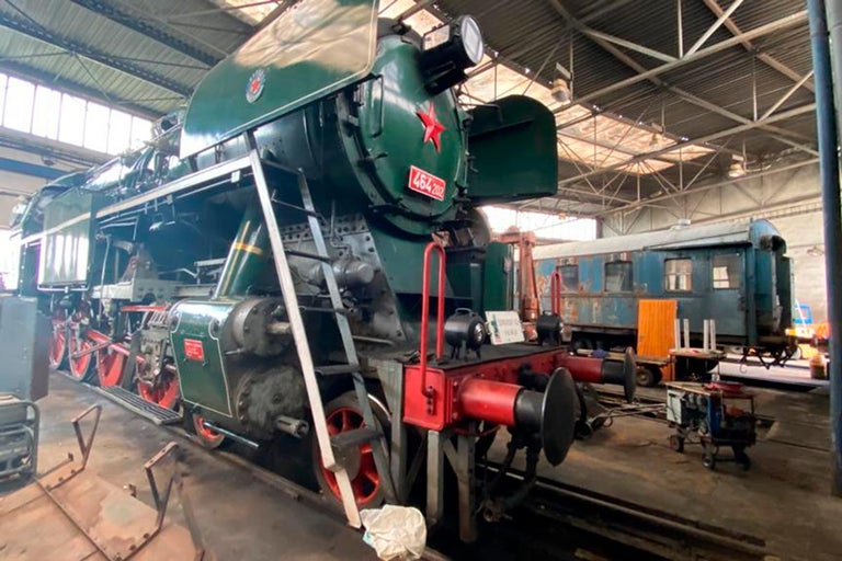 Zelená parní lokomotiva stojí v tovární hale.
