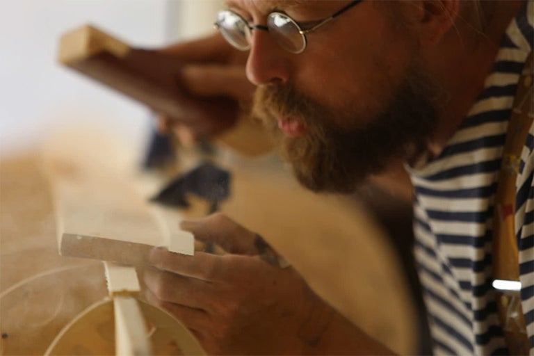 Muž brousí dřevo smirkovacím blokem. Projekt zpracování dřeva.