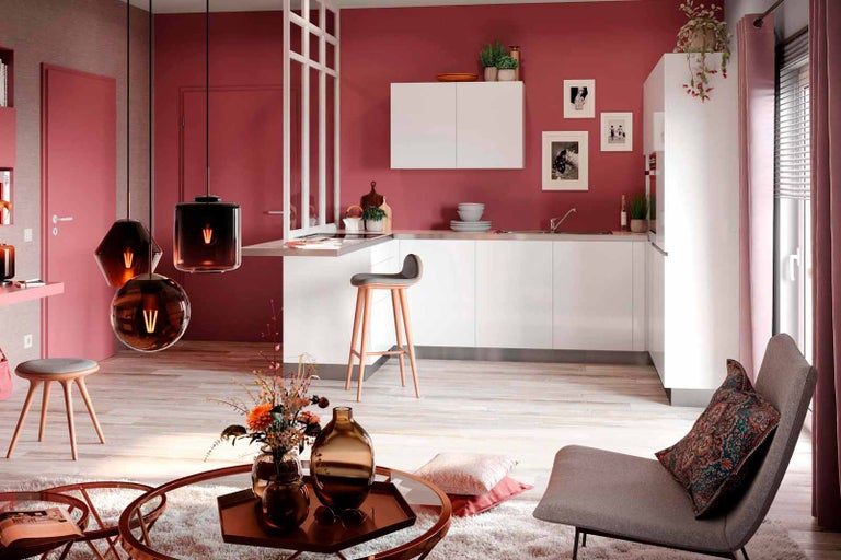 Světlá a moderní obytná kuchyně s bílými skříňkami, barovými stoličkami a závěsnými svítidly