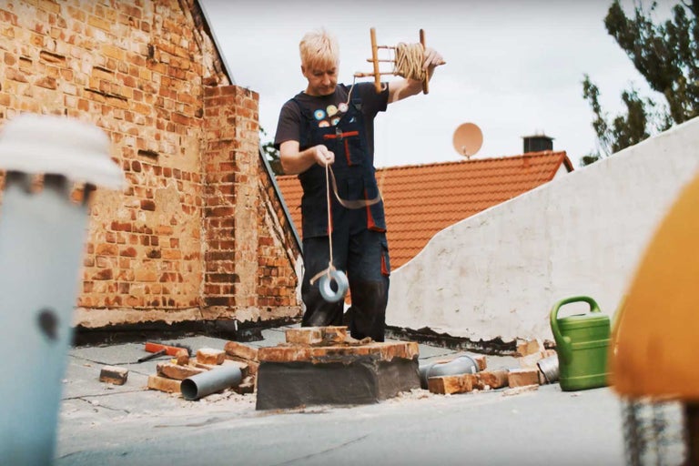 Žena pracuje s zednickou šňůrou na střeše s cihlami.
