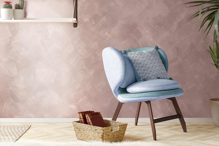 Světlá místnost s pastelovou stěnou, křeslem, košem s knihami a hrnkovými rostlinami
