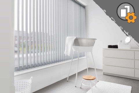 Světlá koupelna s okenními vertikálními žaluziemi, vanou a komodou