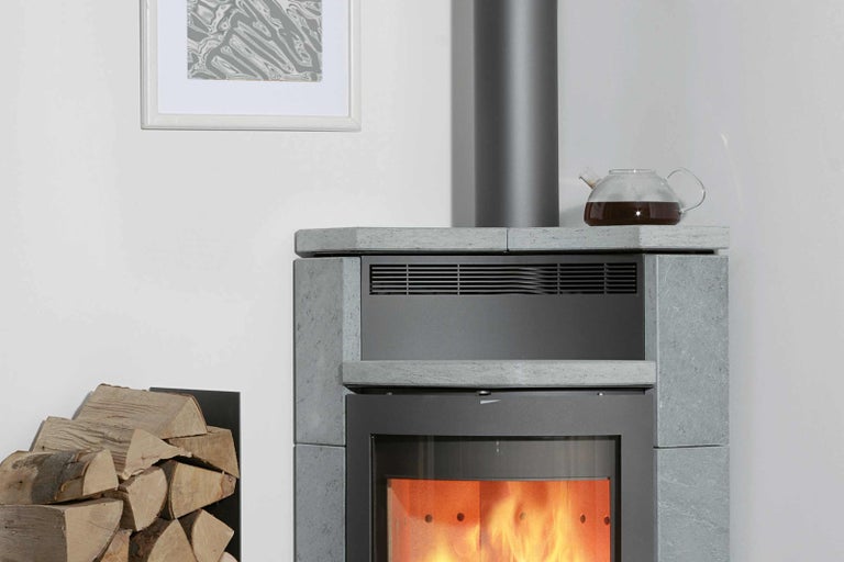 Kamna s hromadou dřeva a čajovou konvicí