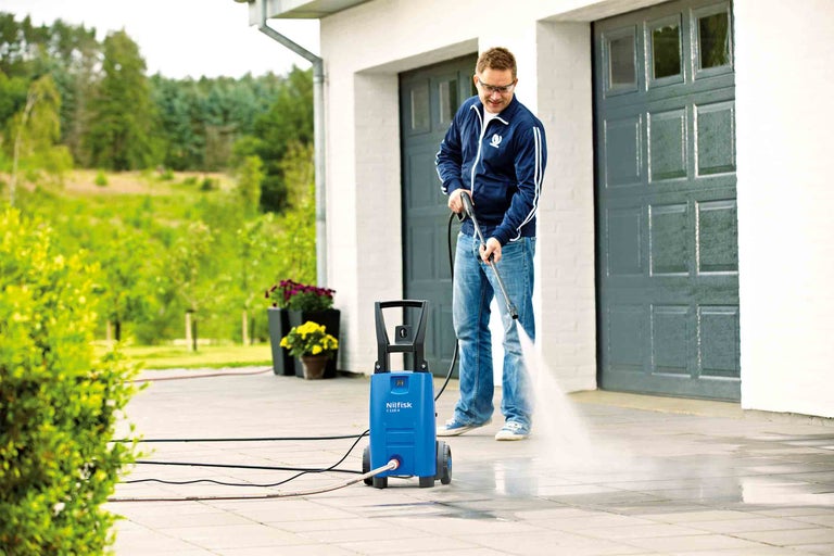 Muž čistí příjezdovou cestu vysokotlakým čističem Nilfisk